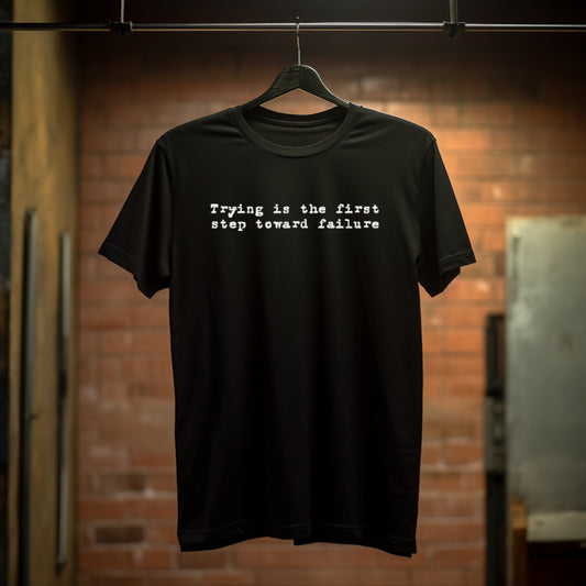 Black t-shirt with "Trying is the first step toward failure" in small white text on the chest in an old typewriter font